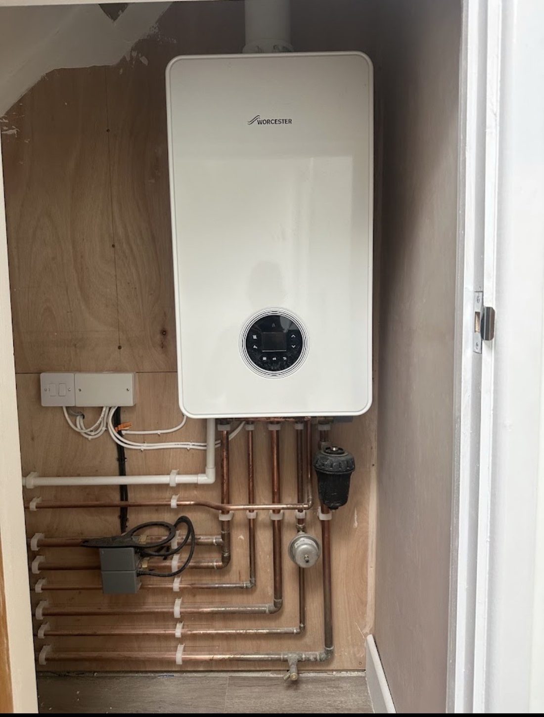 A newly fitted Worcester Bosch combi boiler mounted in a cupboard, with the pipework and controls completed